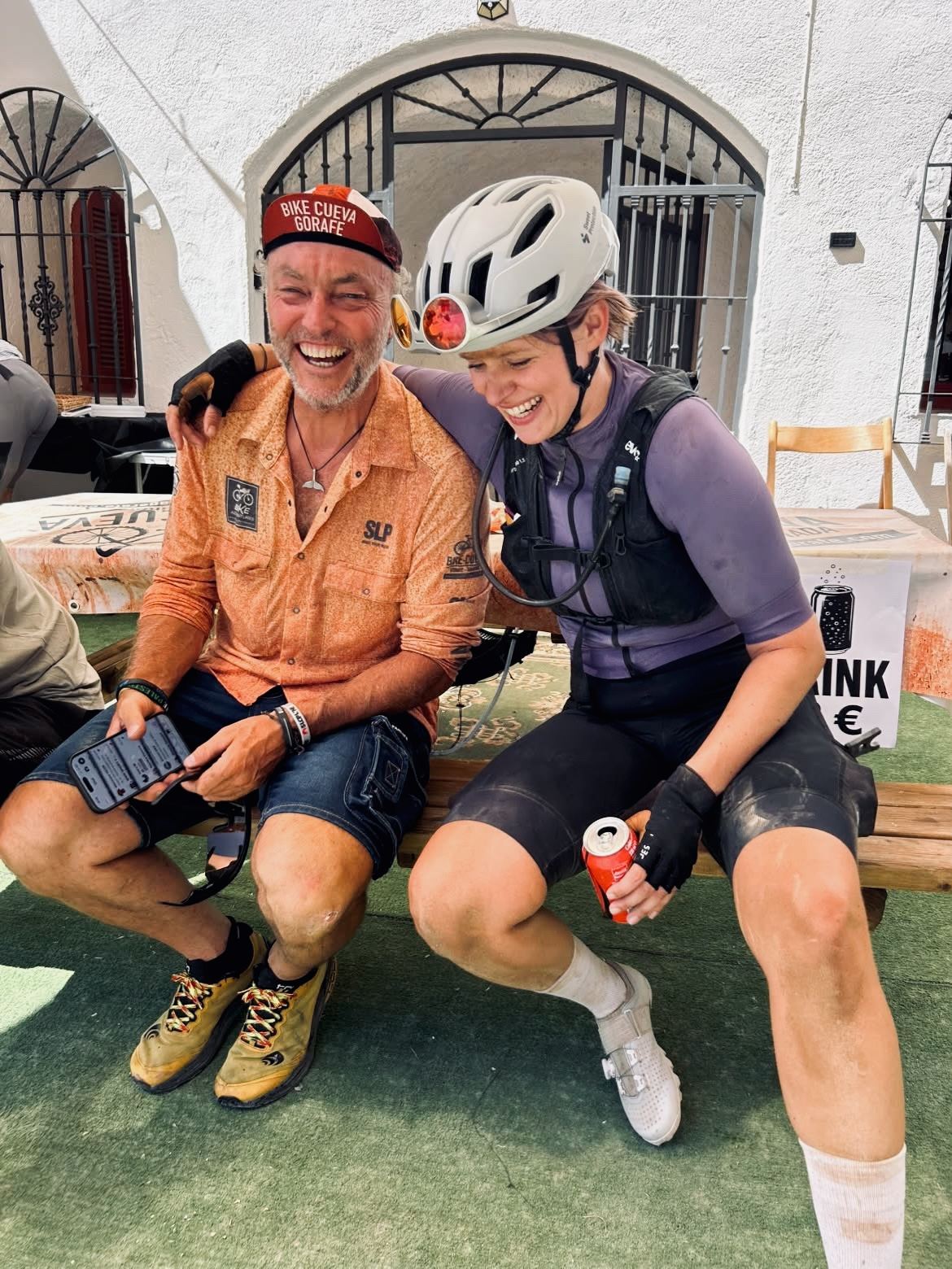 Two riders sitting together on the ground, laughing.