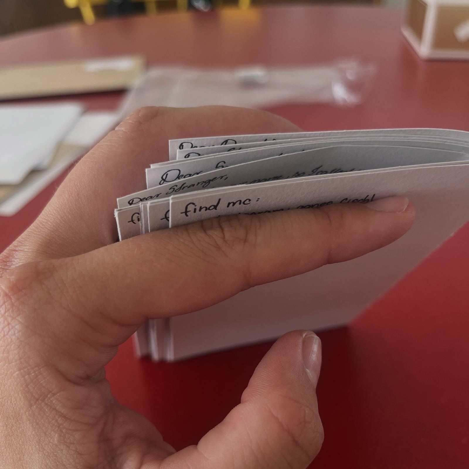 A hand holding the finished stack of letters over the red table.